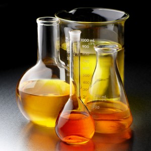 Flasks and beakers filled with bio fuels, shot on textured metal lab table with space for copy